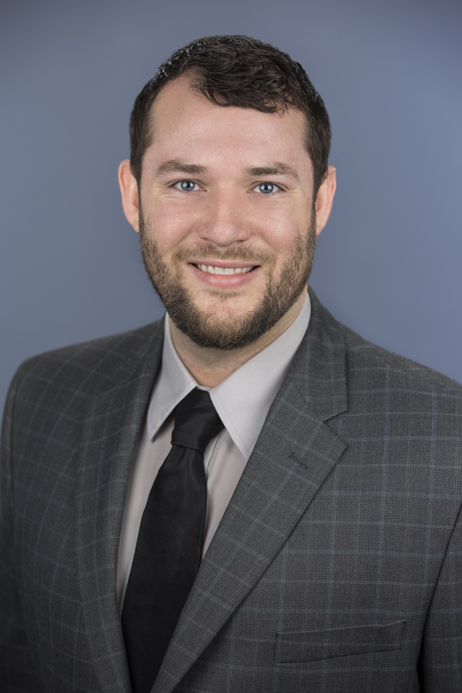 headshot of man wearing brown jacket